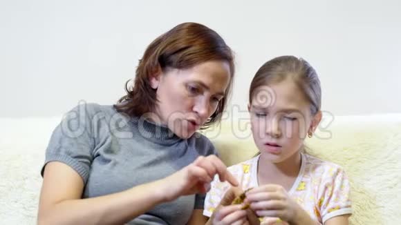 妈妈用针线来教她的女儿一个漂亮的女人和她的女儿缝一件洋娃娃的衣服视频的预览图