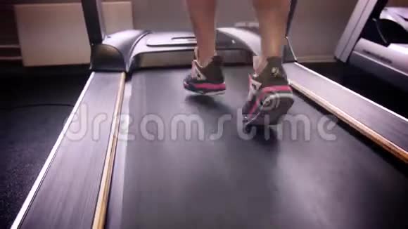 在健身房的跑步机上用运动鞋将女人的腿收起来视频的预览图