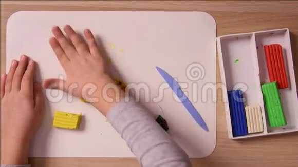 儿童打开一管粘土以鱼的形式贴在工艺品上视频的预览图