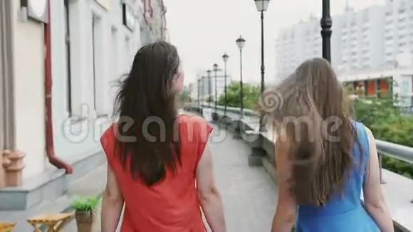 风吹着长长的黑发美丽的年轻女子走在街边经过商店后景慢的莫斯泰迪卡姆射击视频的预览图