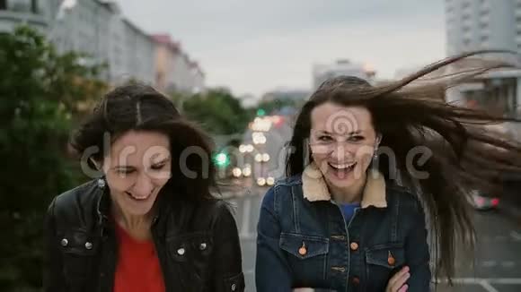 两个美丽的女孩站在桥上微笑着笑着看着镜头风吹着他们的长发视频的预览图
