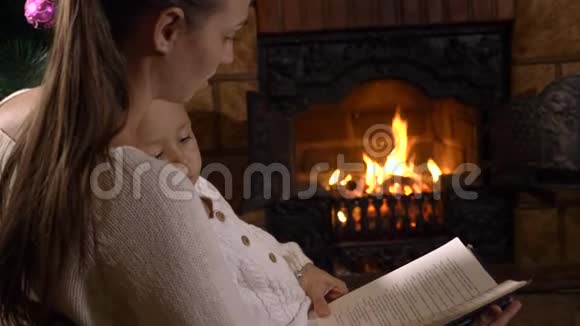 妈妈带着小女儿在壁炉和圣诞树附近看书视频的预览图