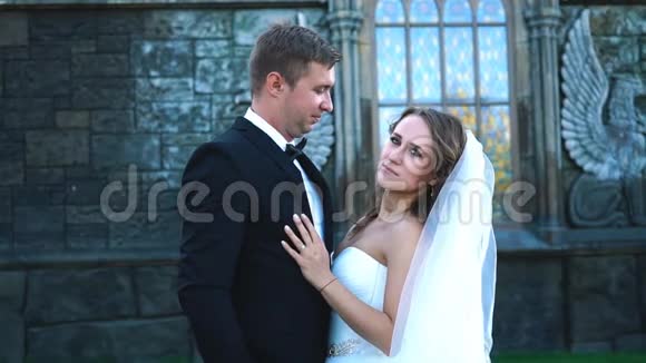 英俊浪漫的新郎和美丽的金发新娘在老墙城堡附近摆姿势视频的预览图