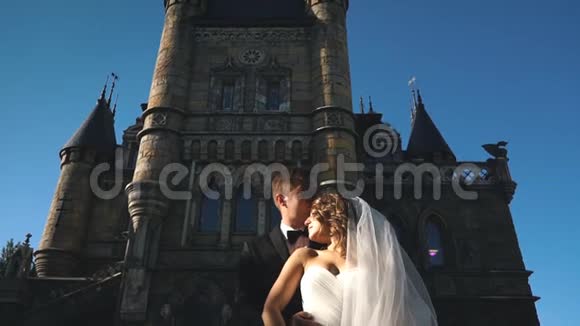 英俊浪漫的新郎和美丽的金发新娘在老墙城堡附近摆姿势视频的预览图