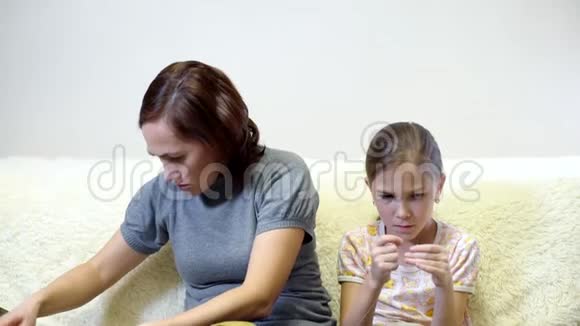 妈妈用针线来教她的女儿一个漂亮的女人和她的女儿缝一件洋娃娃的衣服视频的预览图