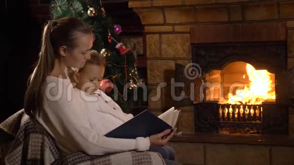 妈妈带着小女儿在壁炉和圣诞树附近看书视频的预览图