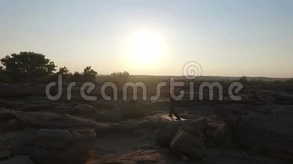 一个在日落时分在岩石上从事中国体操的人空中飞行视频的预览图