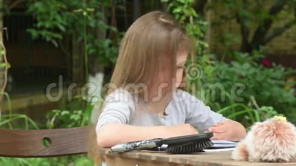 女孩坐在院子里的一张桌子旁鬼鬼祟祟地把舌头伸到架子上视频的预览图