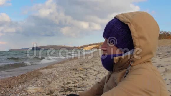 女孩坐在海边沉思波浪美丽的风景视频的预览图