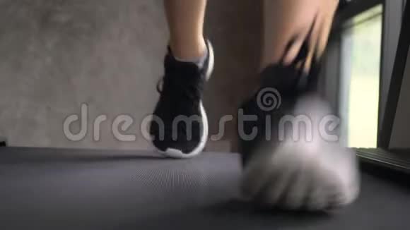 年轻女子在健身房跑步机上慢跑正面向上看视频的预览图