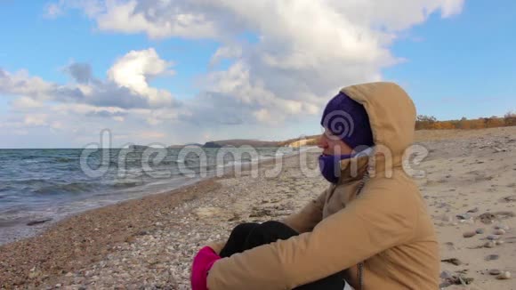 女孩坐在海边沉思波浪美丽的风景视频的预览图