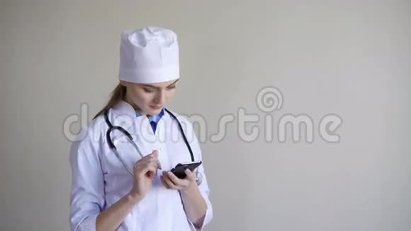 年轻的女医生坐在医院里拿着智能手机微笑着视频的预览图
