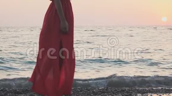 一个穿红裙子的女孩正沿着海滨散步视频的预览图