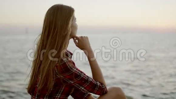 一个年轻女孩坐在海边看地平线视频的预览图