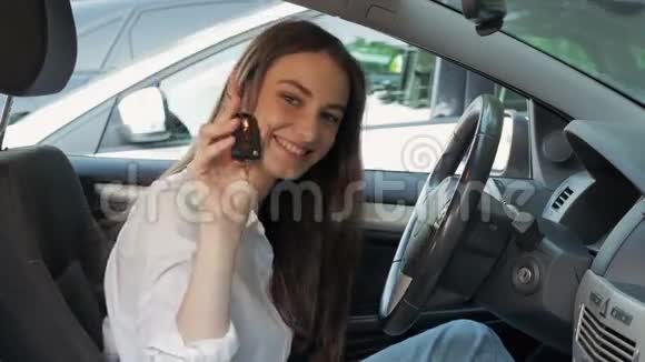 年轻可爱的幸福女人在获得驾驶执照后展示汽车钥匙美丽的年轻驾驶学生开车视频的预览图