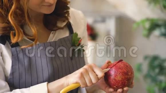 厨师女厨师围着围裙在厨房用刀子切石榴视频的预览图
