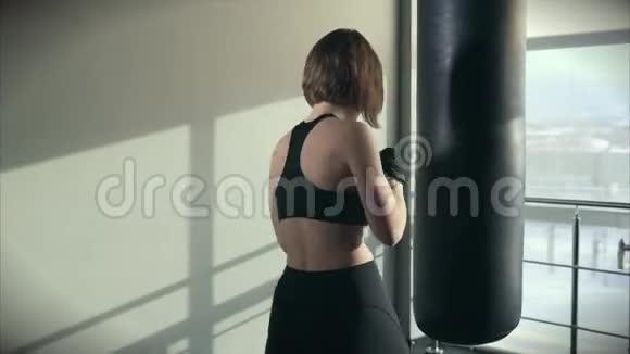 运动女性从事拳击运动在健身俱乐部里训练一个拳击包视频的预览图