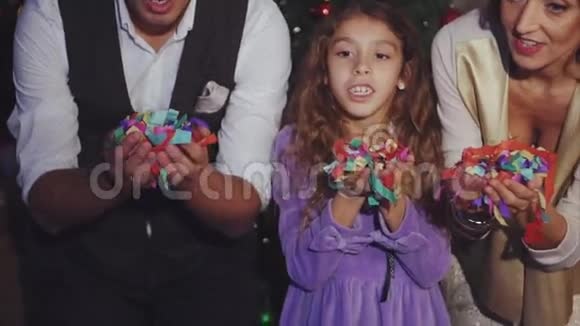 欢乐家庭的慢镜头吹出五颜六色的圣诞彩纸视频的预览图
