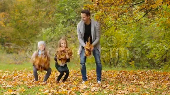 在秋日的户外活动中一个微笑的年轻家庭玩得很开心到处扔树叶视频的预览图