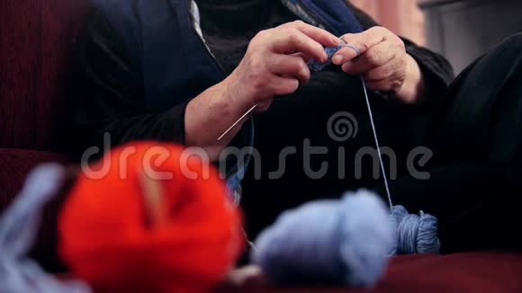 老年女性养老金领取者的双手编织坐在沙发上的羊毛袜子老年妇女在家里的爱好视频的预览图