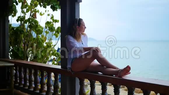 女孩坐在露台上朝大海看视频的预览图