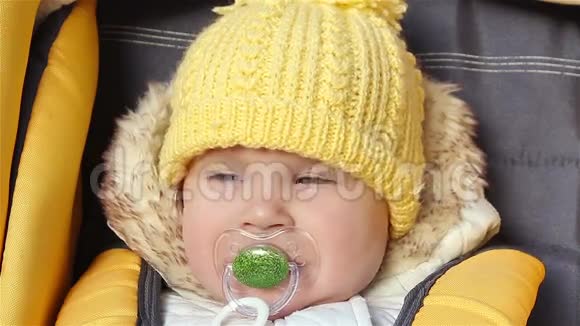 婴儿坐在婴儿车厢里奶嘴在吮吸视频的预览图