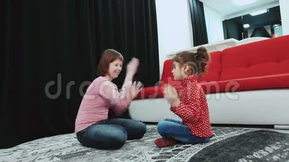 两个女孩其中一个患有唐氏综合症坐在家里的地毯上玩得开心视频的预览图