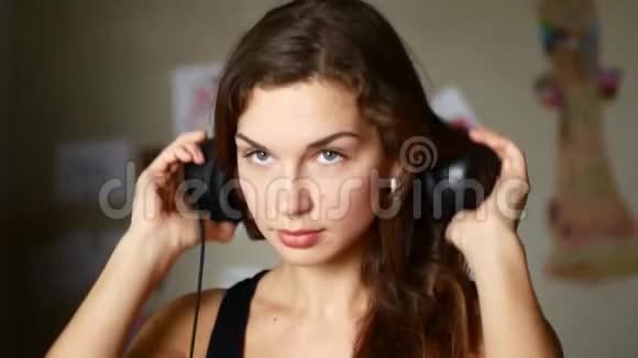 迷人的年轻女子戴着耳机听音乐播放器上的音乐视频的预览图