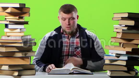 坐在书桌前的人翻阅着一本教科书绿色屏幕视频的预览图