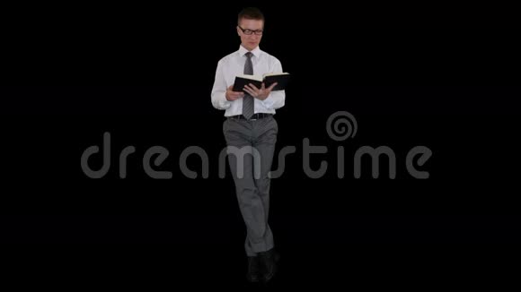 年轻的商人戴着眼镜看着一本书坐着看着黑色的股票录像视频的预览图
