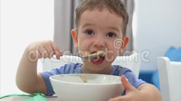 小可爱的孩子正坐在一张桌子旁吃着自己的燕麦片宝宝吃得心甘情愿快乐童年的概念视频的预览图