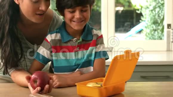 快乐的母亲给儿子们放苹果饭盒视频的预览图