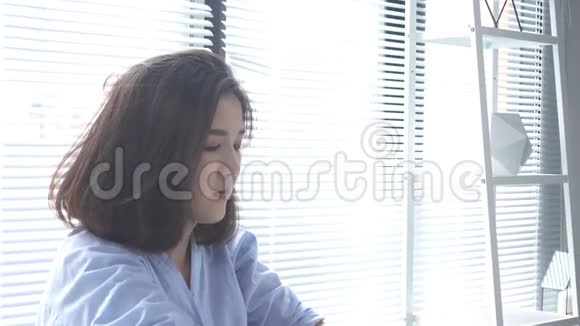 美丽的年轻拉斯特亚裔妇女在家里坐在客厅里用笔记本电脑工作亚洲商界女性工作视频的预览图