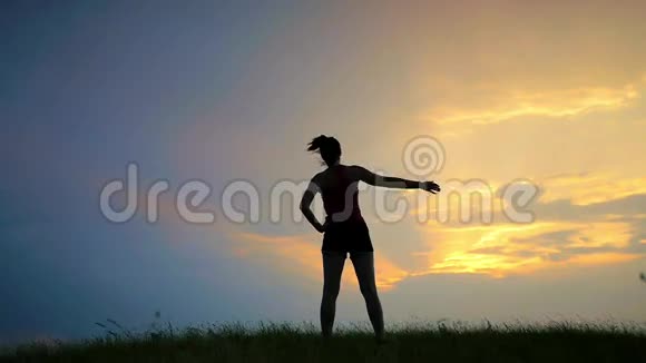 日落时练习瑜伽的年轻女子剪影视频的预览图