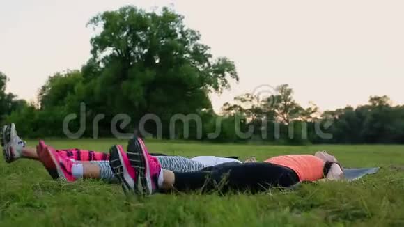 感受你的腹肌女孩一群穿着运动服的年轻人在夏天的草地上做体育锻炼视频的预览图