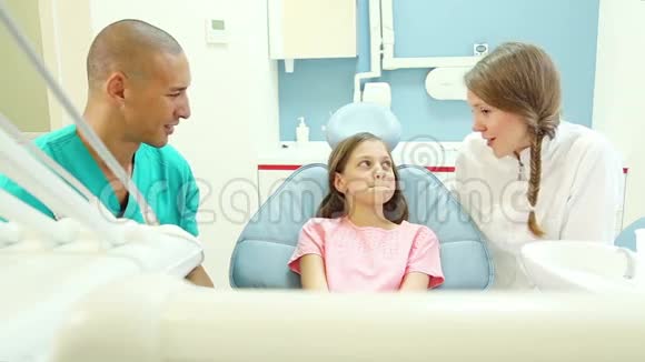 牙科助理和牙医在检查前给小女孩看口镜视频的预览图