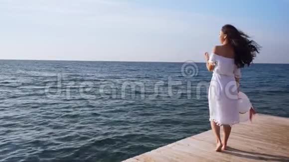 年轻女子站在木墩上望着大海视频的预览图