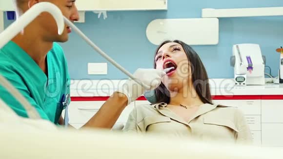 当牙医助理试着检查她的牙齿时年轻女性开始大笑视频的预览图