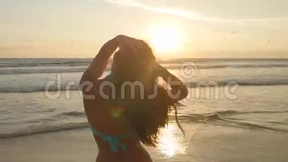 美丽的女孩长发在日出时摆在海边穿着比基尼站在附近的漂亮年轻女子视频的预览图