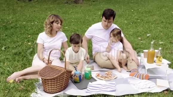 野餐时孩子们在草地上休息的幸福家庭视频的预览图