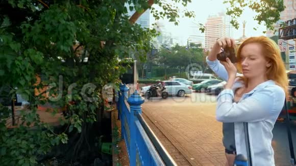 一个拿着相机的女人走过一个现代化的大城市的街道视频的预览图