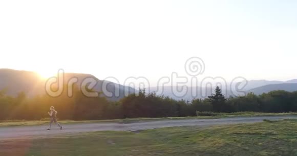 日落时分一个女人在乡间的路上奔跑视频的预览图