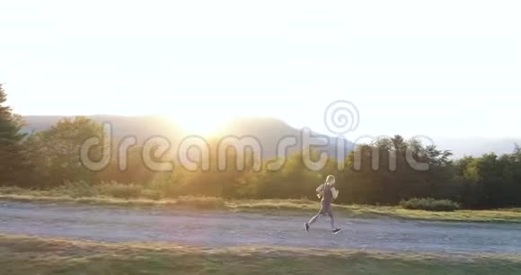 日落时分一个女人在乡间的路上奔跑视频的预览图