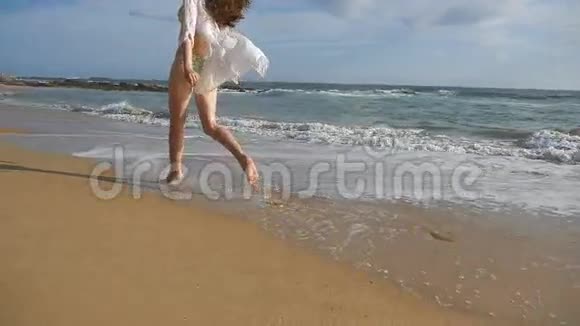 穿比基尼和衬衫的快乐女人在海边跑步年轻美丽的女孩享受生活和海上乐趣视频的预览图