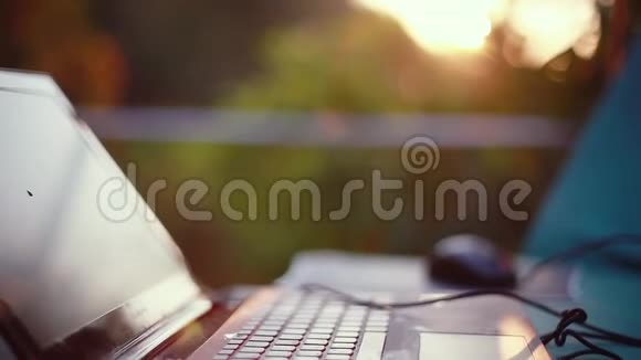 笔记本电脑和鼠标在户外日落与美丽的镜头耀斑效果1920x1080视频的预览图