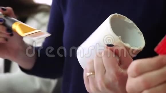 设计师用画笔绘制并在白色陶瓷杯上油漆视频的预览图