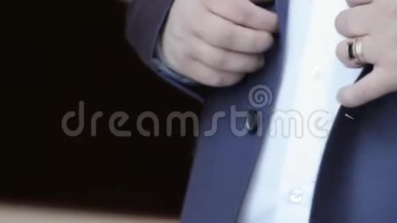 一个男人在一件时髦的蓝色夹克上扣扣子视频的预览图