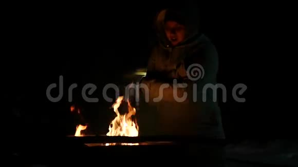 小女孩晚上站在篝火旁取暖搓着他的手拍手1920x1080视频的预览图