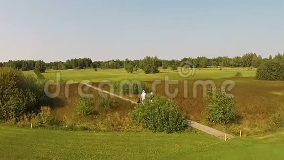 一架无人机飞过一个绿色高尔夫球场人们在那里散步视频的预览图