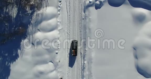 对沿着积雪覆盖的道路行驶的汽车进行空中勘测无人机在4K拍摄的视频视频的预览图